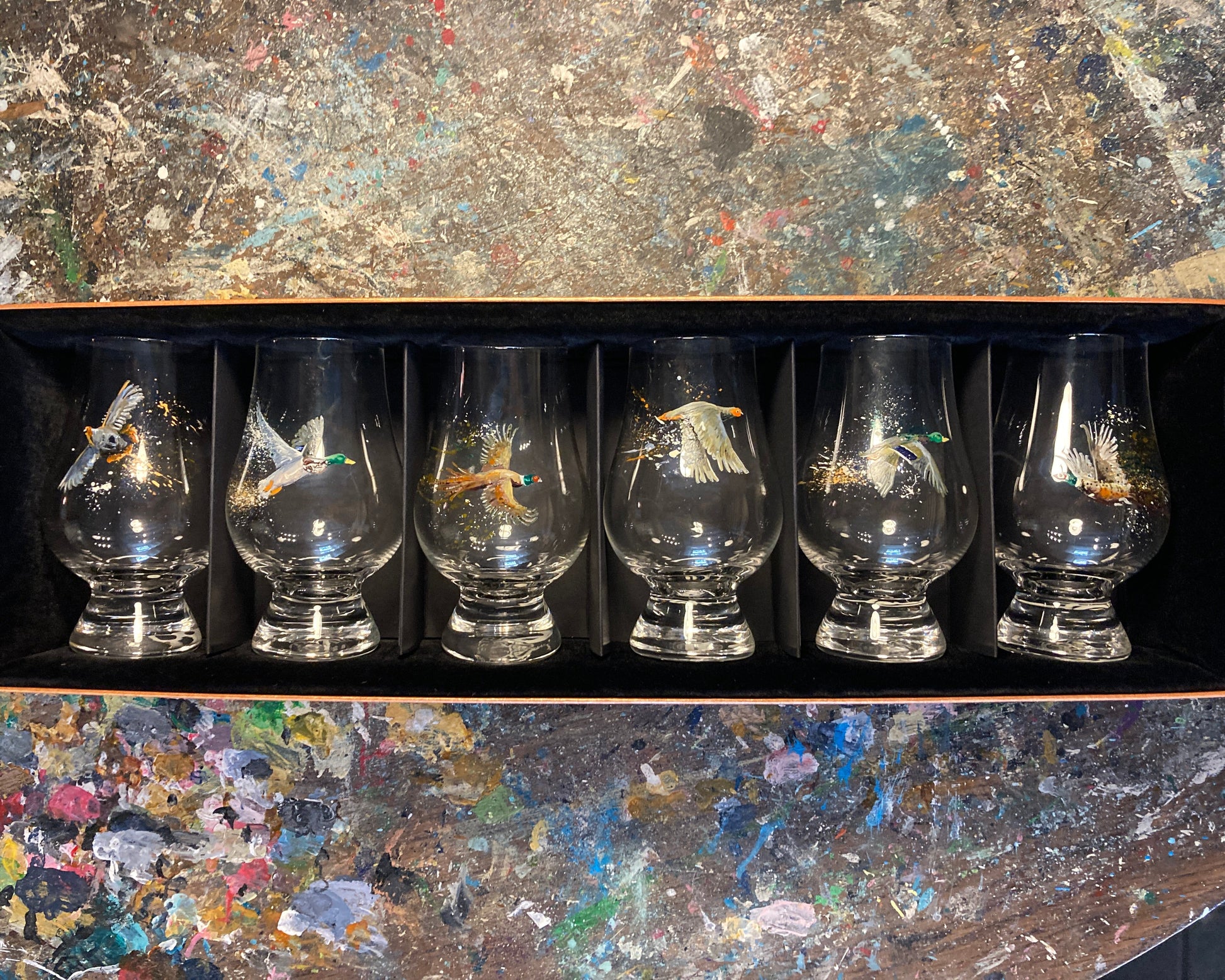 Set of six glass tumblers with Game Bird designs in a black box on a textured surface.